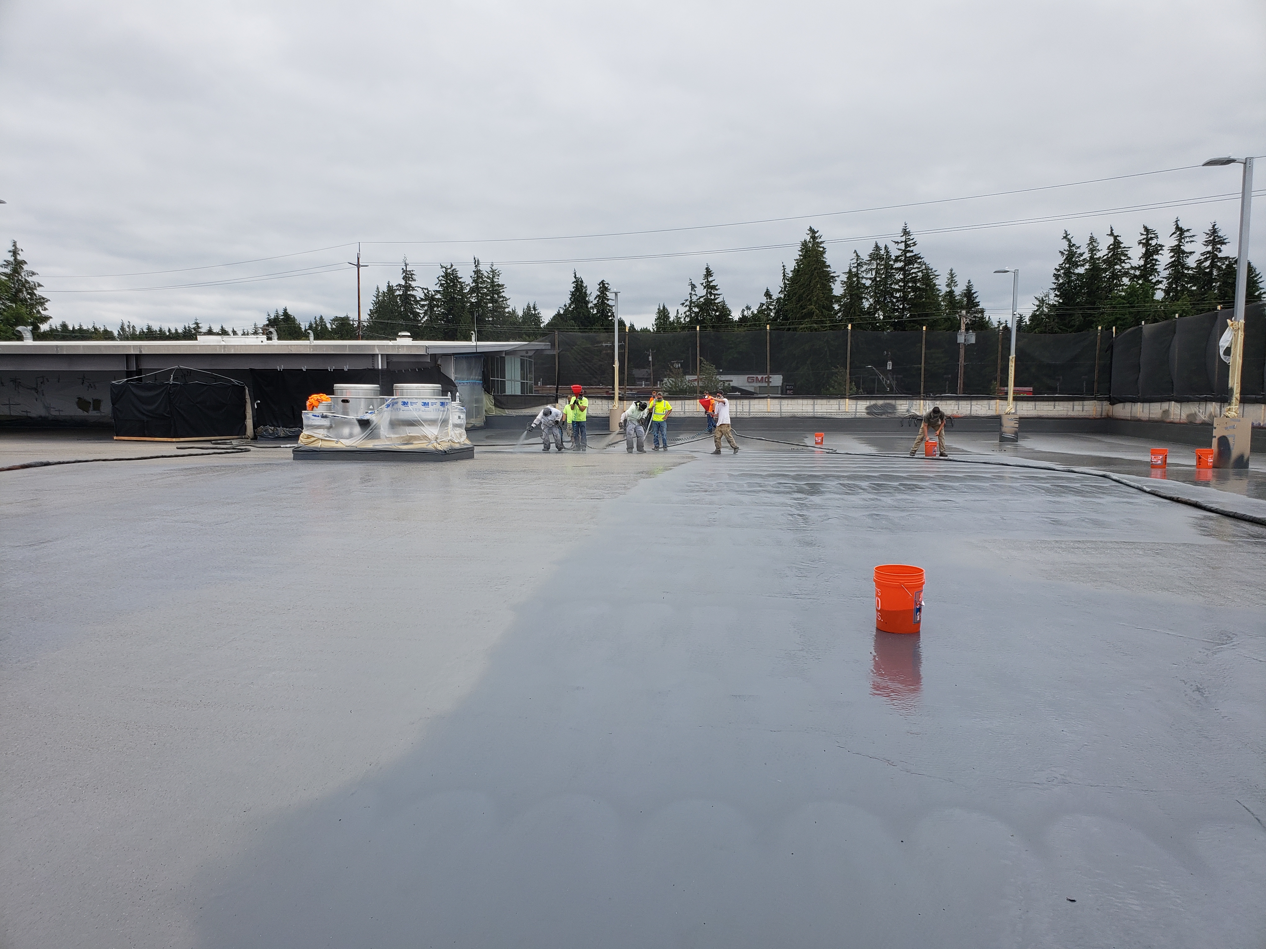 Aged single-ply commercial roof being restored with liquid membrane
